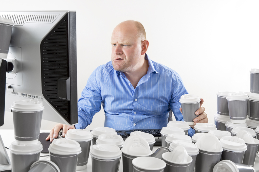 Overworked and exhausted office worker drinks too much coffee.